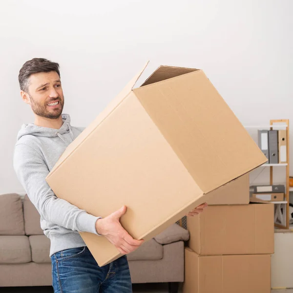 Man transferring heavy box while moving in new apartment — Stok fotoğraf