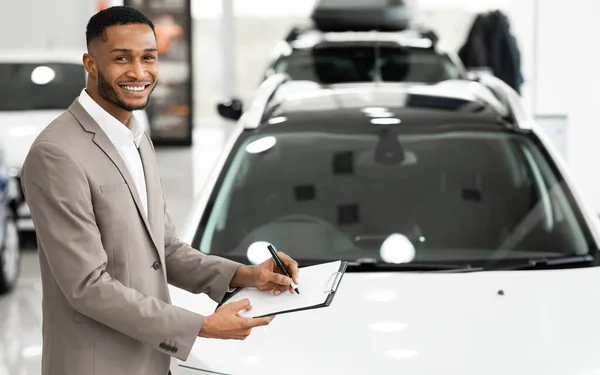 Gerente de vendas de carro alegre que está perto do automóvel na loja — Fotografia de Stock