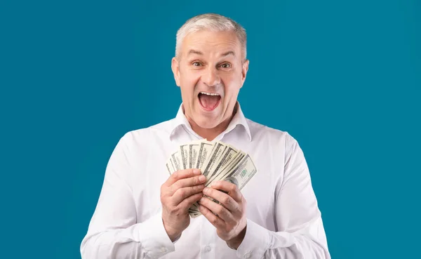 Happy mature man holding money at studio — Stock fotografie