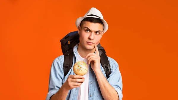 Pensive backpacker holding globe, thinking where to go — Zdjęcie stockowe