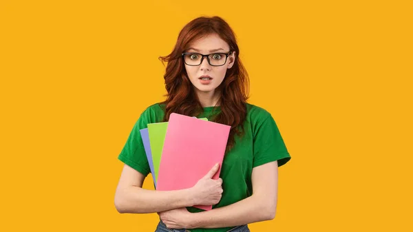 Shocked student girl holding books standing on yellow background, panorama — Stok fotoğraf