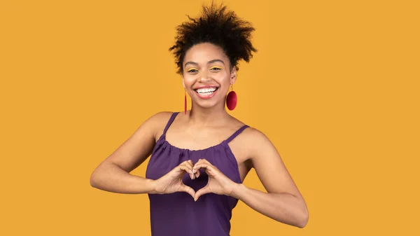 Sorrindo mulher negra mostrando gesto de coração no estúdio — Fotografia de Stock