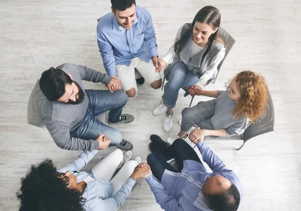 Group therapy patients sitting in circle and holding hands during session — Stock Photo, Image