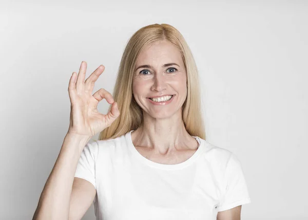 Happy mature woman gesturing ok sign and smiling — Stockfoto
