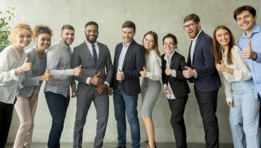 Cheerful young business team showing thumbs up