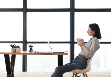 Young woman using laptop and drinking hot coffee