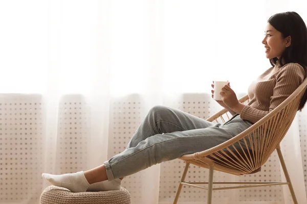 Menina sonhadora desfrutando de café quente perto da janela em casa — Fotografia de Stock