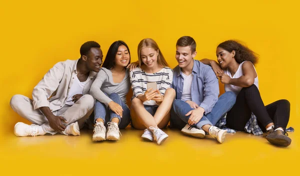 Teenagers sitting on floor and looking at smartphone screen — Stok fotoğraf