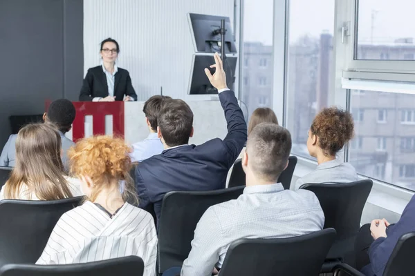 Businessman raising hand at seminar, having question to speaker — Stockfoto