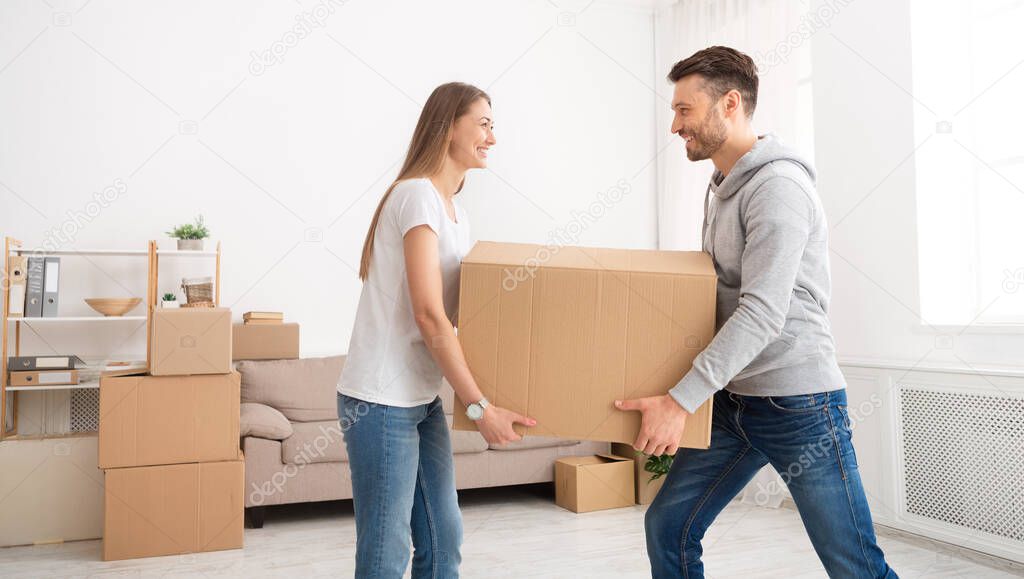 Happy young couple moving in new flat with cardboard boxes