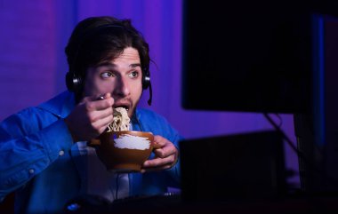 Guy Eating Noodles Sitting At Computer At Home At Night