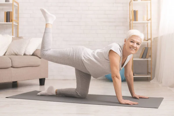 Senior fitness lady de pie a cuatro patas, enderezando la pierna — Foto de Stock