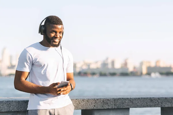 Smiling sportsman enjoying music while walking down the bridge — Stok fotoğraf