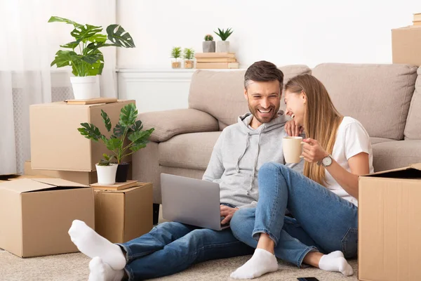 Happy couple sitting among moving boxes and having fun — Stock Fotó