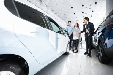 Dealer Showing Family New Auto In Dealership Store