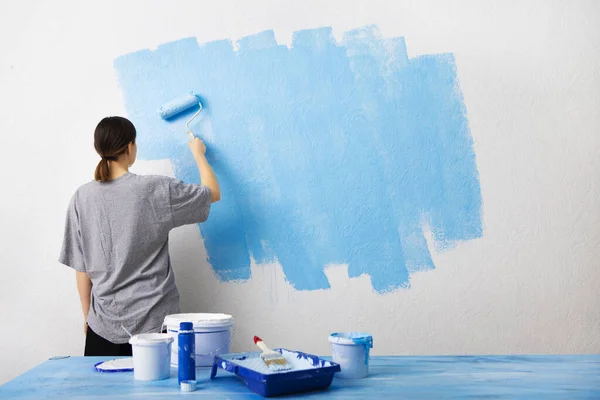 Mujer pintando pared interior con rodillo de pintura — Foto de Stock