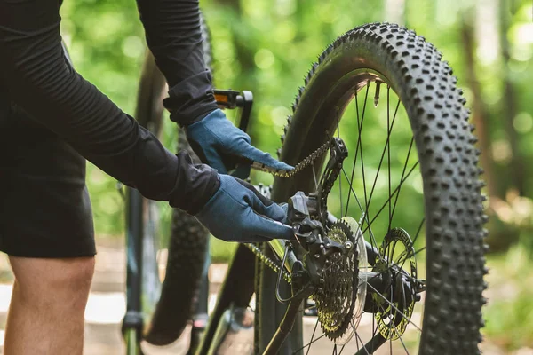 Bicyclist fixing bike chain while riding in forest — Stock Fotó
