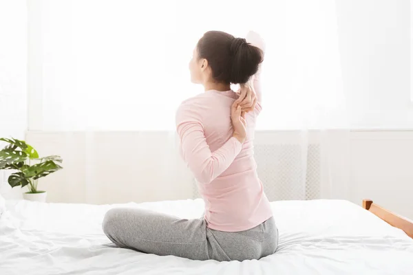 Joven mujer yoga haciendo que las manos se bloqueen detrás de la espalda en la cama —  Fotos de Stock