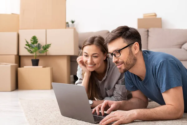 Happy couple searching for ideas during repair and looking at laptop — Stockfoto