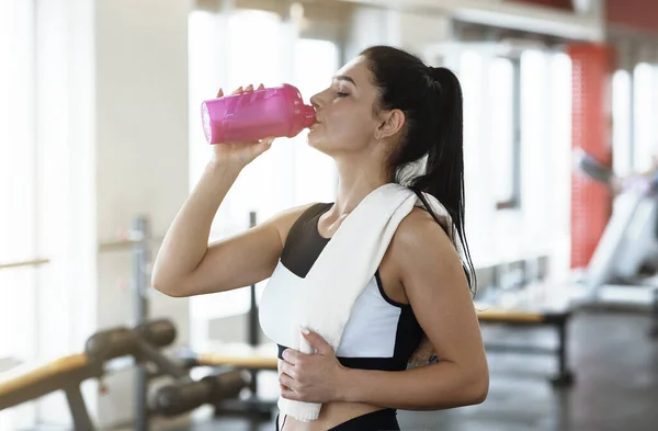 Keep hydrated. Young woman drinking water or protein cocktail in gym — ストック写真