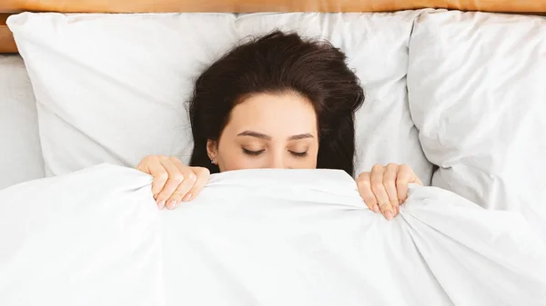 Millennial girl hiding under blanket in bed, panorama — Stock fotografie