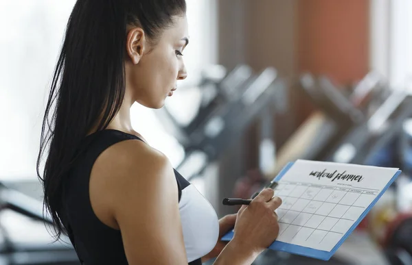 Personal trainer with clipboard making workout plan in gym — Stock Photo, Image