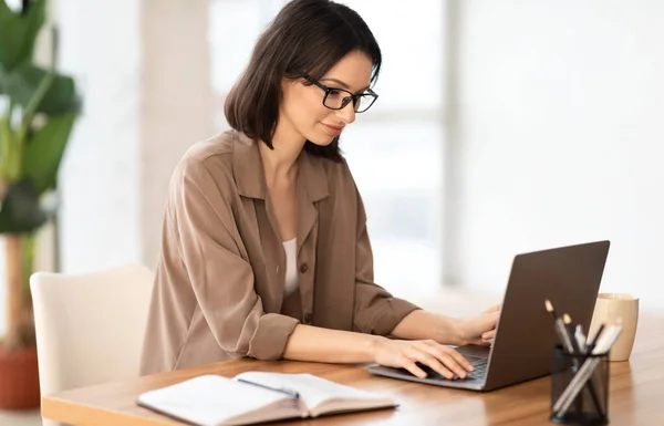 Bella ragazza che lavora sul suo computer portatile in ufficio contemporaneo — Foto Stock