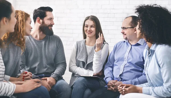 Psicólogo sonriente hablando con los miembros del grupo en la sesión de terapia en rehabilitación —  Fotos de Stock