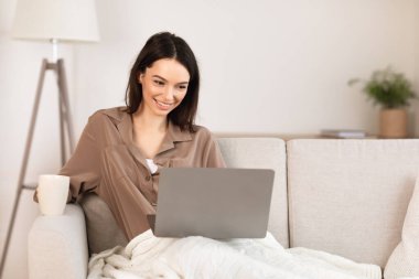 Young woman using laptop lying on the couch