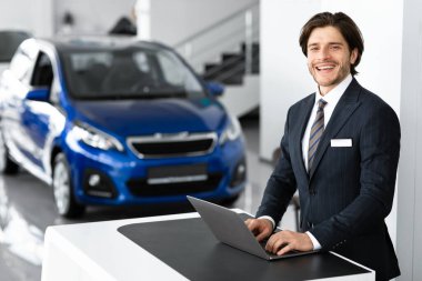 Car Sales Manager Standing In Luxury Dealership Office