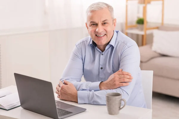 Senior man using laptop at office and looking at camera — Stock Fotó