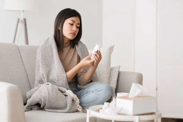 Girl with cold and flu reading instructions on medicine bottle — 图库照片