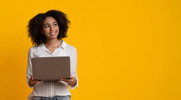 Mujer afro pensativa con computadora portátil mirando hacia otro lado sobre fondo amarillo — Foto de Stock