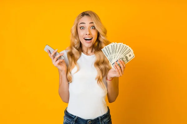 Make money online. Surprised woman holding smartphone and money — ストック写真