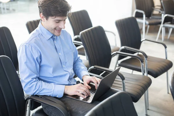 Hombre de negocios seguro usando el ordenador portátil en la sala de conferencias vacía — Foto de Stock