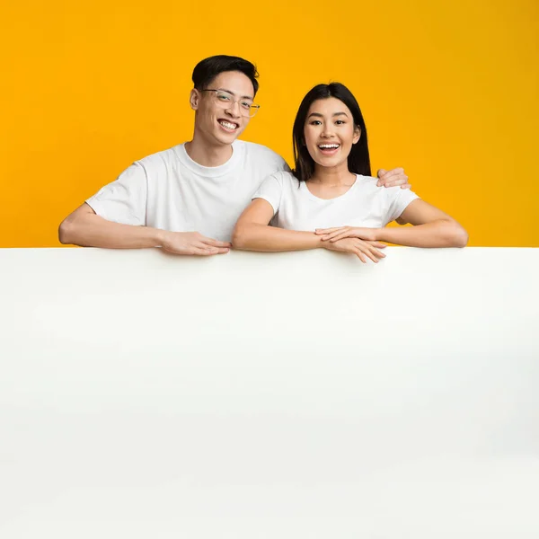 Asian couple leaning on big blank board for advertisement — Stok fotoğraf