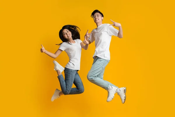 Crazy asian millennial couple jumping in air — ストック写真