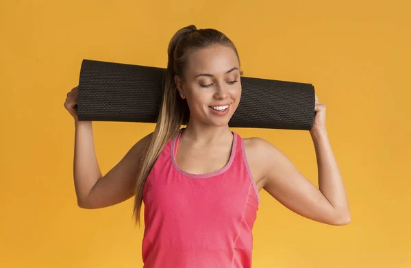 Sporty Woman With Yoga Mat Behind Her Head On Yellow Background — Stock fotografie