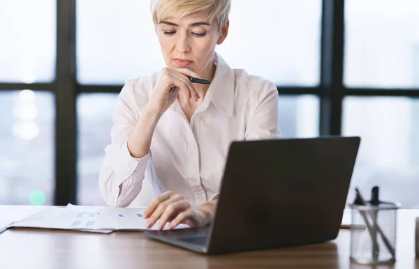 Mulher no laptop leitura relatório de negócios sentado no escritório — Fotografia de Stock