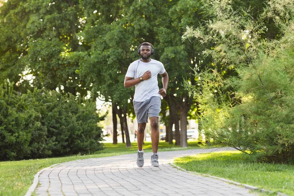 Sporty african guy is jogging in the park — Stock fotografie