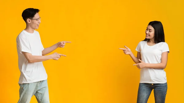 Asian man and woman pointing at copy space between them — Stok fotoğraf