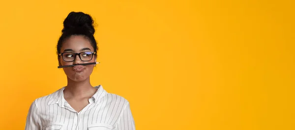Black girl in glasses keeping pencil like mustache and looking aside — Stockfoto