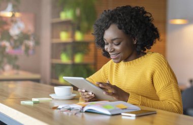 African businesswoman using digital tablet in cafe