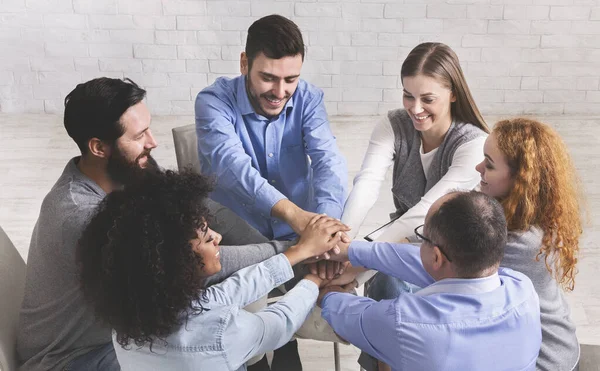 Happy people sitting in trust circle and putting hands together — Stock Photo, Image