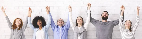 Boldog sokszínű emberek csoportja fogja egymás kezét, felemeli a karját, panoráma — Stock Fotó