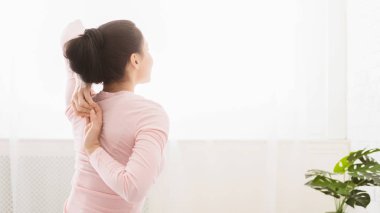 Young woman stretching hands on bed at home, panorama