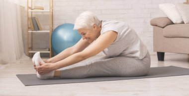 Active senior woman doing stretching exercises at home