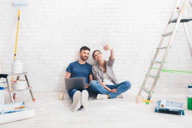 Happy couple taking selfie while choosing project on laptop