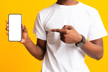 Unrecognizable african guy holding latest phone on yellow