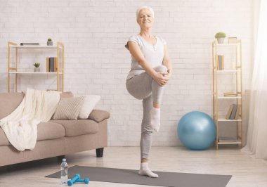 Active senior woman warming up at home